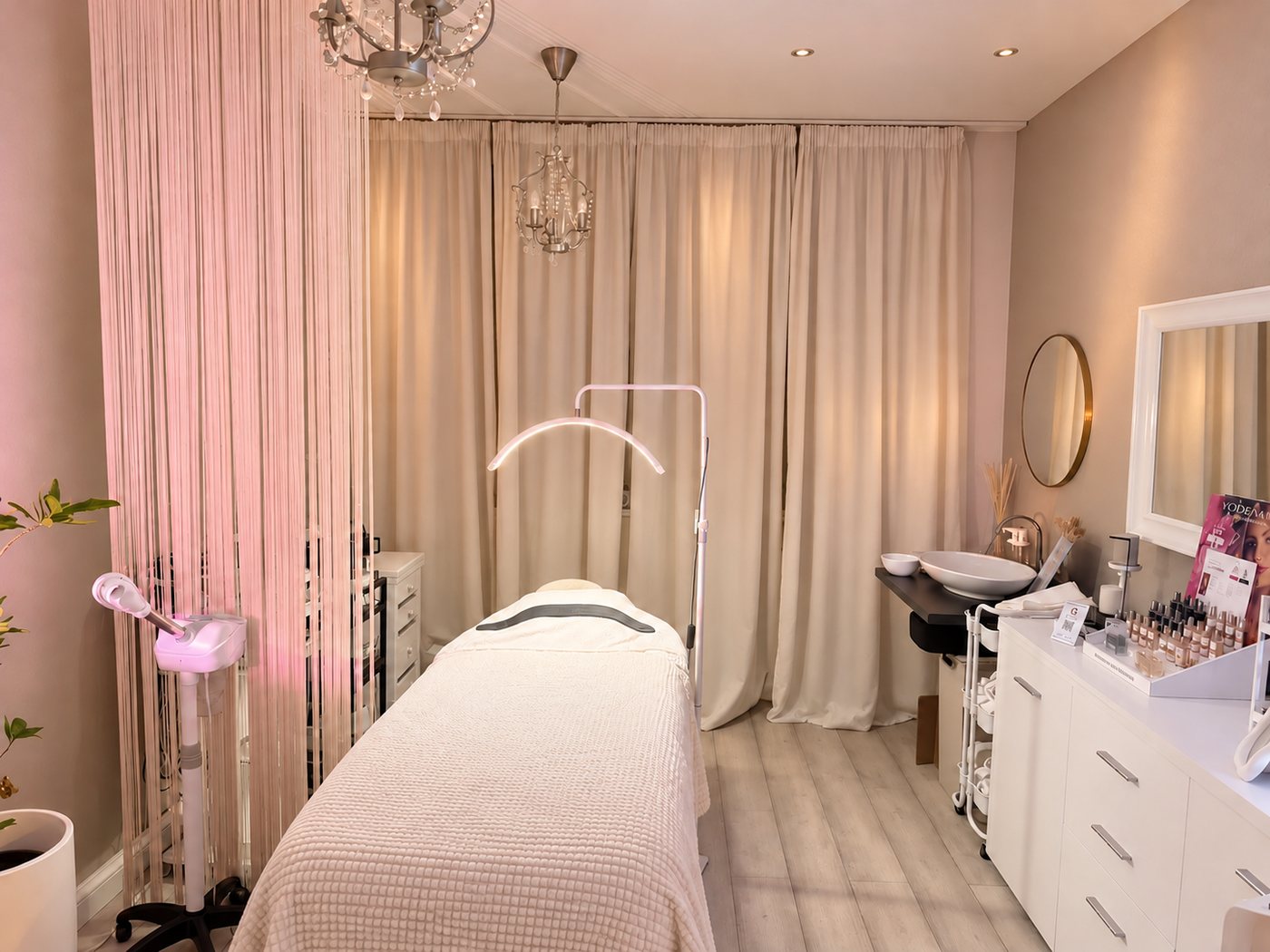 Behandlungsraum der Mahshid Beauty Bar mit Liege, Ringlicht und rosé beleuchtetem Fadenvorhang